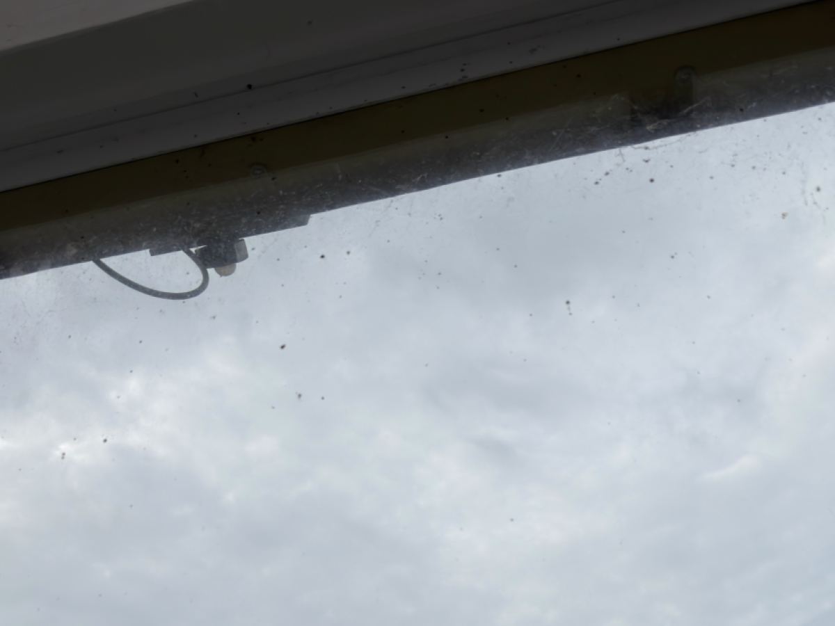 Ein Dachfenster mit verschmutzter Scheibe und Spuren am Rahmen