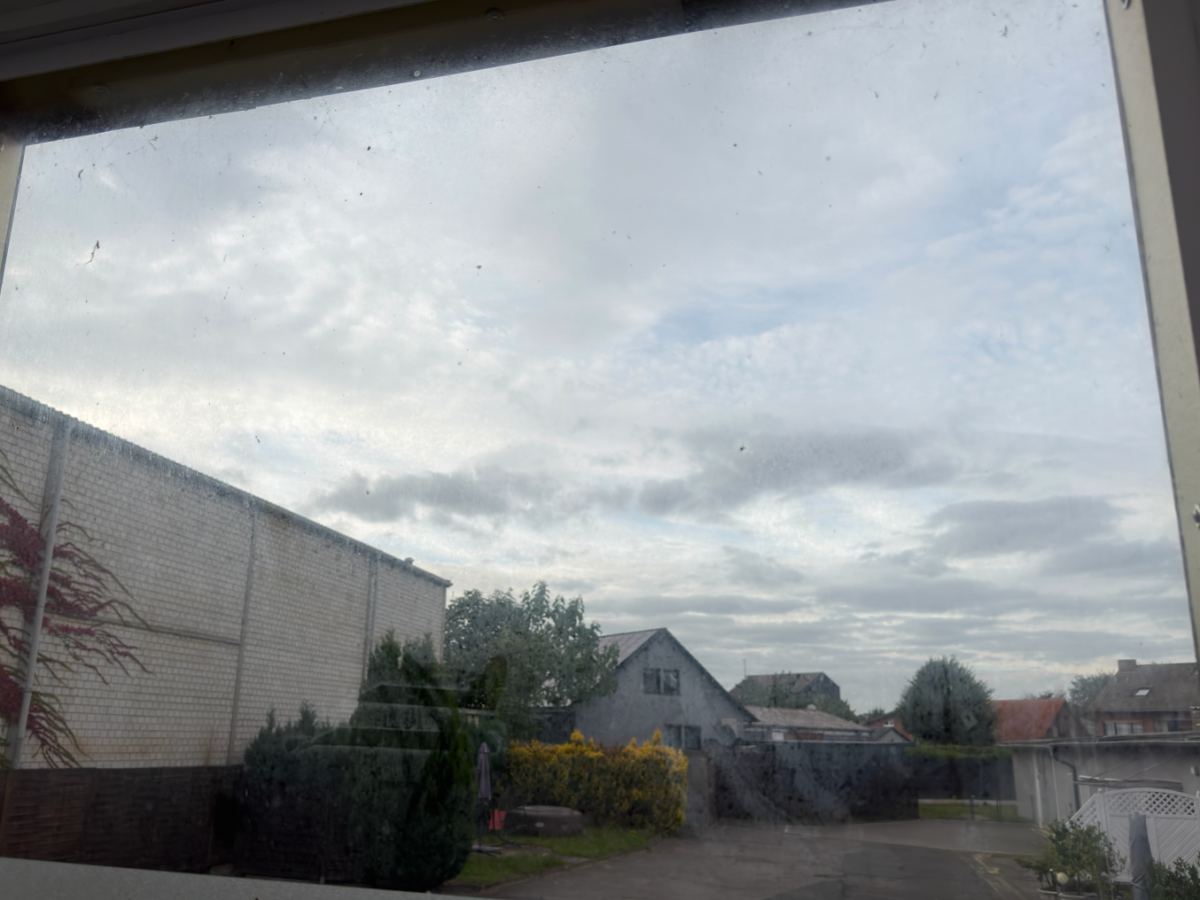 Ein Fenster mit Staub und Flecken, der Blick nach draußen ist trübe